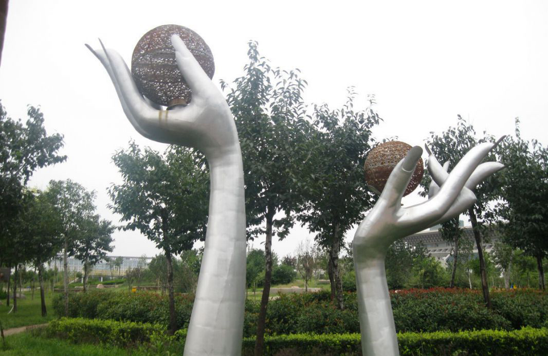 公园不锈钢拿着镂空球的手雕塑图片